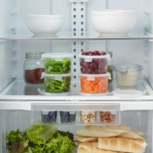 Small portion control storage containers stacked neatly inside a refrigerator drawer. These are 1 2 cup containers with lids.