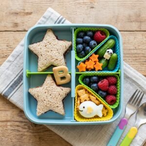 Creative bento box dividers used to organize a child's school lunch with star-shaped sandwiches.