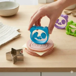 A close-up demonstration showing how to press bento box cutters into sliced cheese and ham.